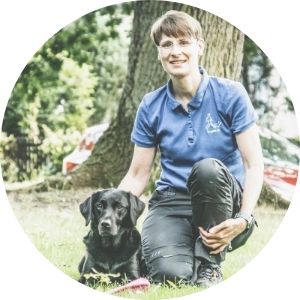 Hundetrainerin mit schwarzen Labrador im Park, positive Ausbildung und Tierpsychologie, Felltraum, Schweizer Hundeschule, Naturerlebnis mit Hunden.